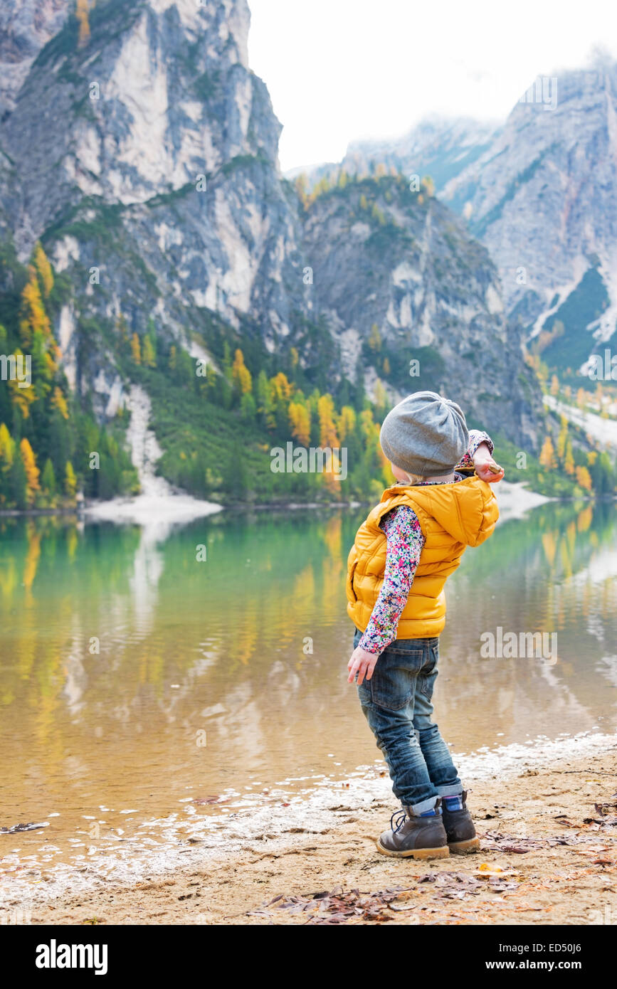 Bambino che lanciano pietre mentre sul lago di Braies in alto adige, italia Foto Stock
