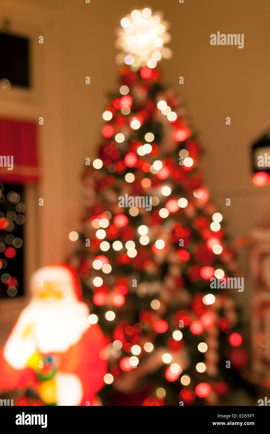 Albero di Natale decorato con luci Candy Cane ornamenti Tree Topper e Santa Claus statua sfocato sfocati sfondo bokeh di fondo Foto Stock