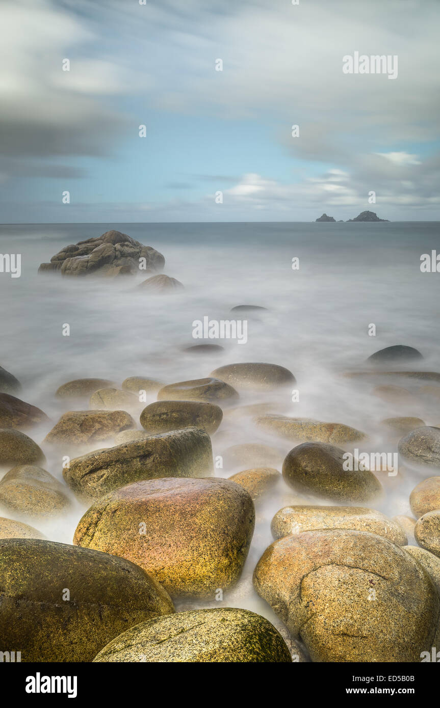 Una lunga esposizione come le onde si infrangono su rocce distintivo a Porth Nanven, Cornwall. Foto Stock