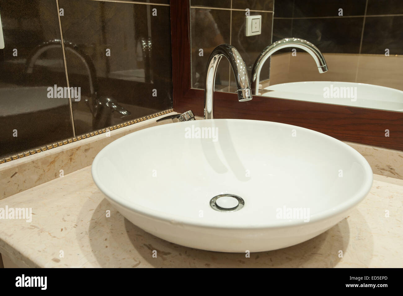 Bianco ornato sink sul bancone di marmo accanto a specchio in un appartamento di lusso bagno Foto Stock