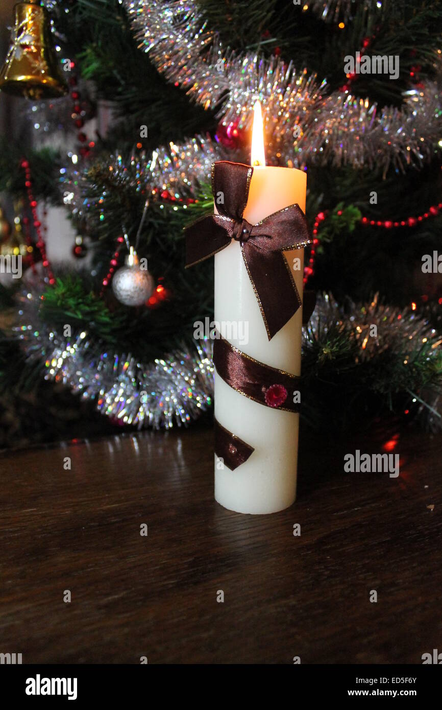 Bella bianca spessa candela che brucia decorato marrone con nastro di raso e la prua Foto Stock