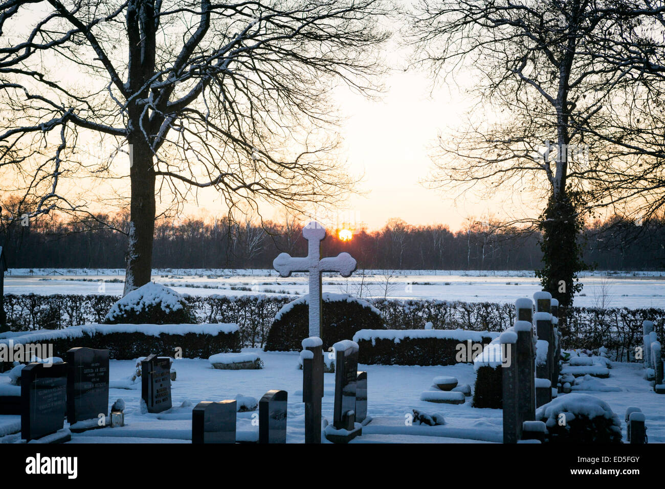Cimitero in inverno con il tramonto del sole e neve Foto Stock