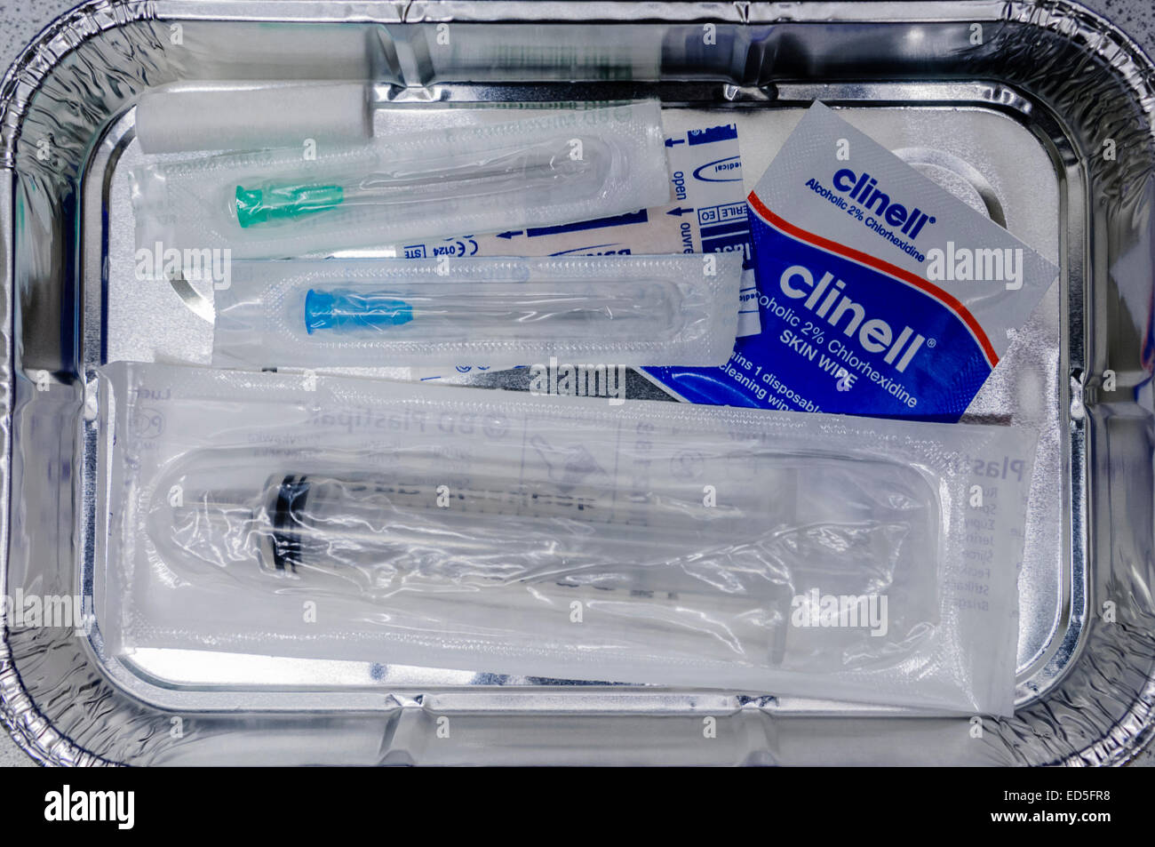 Vassoio di alluminio riempito con aghi, siringa e altre apparecchiature pronte a prendere il sangue da un paziente. Foto Stock