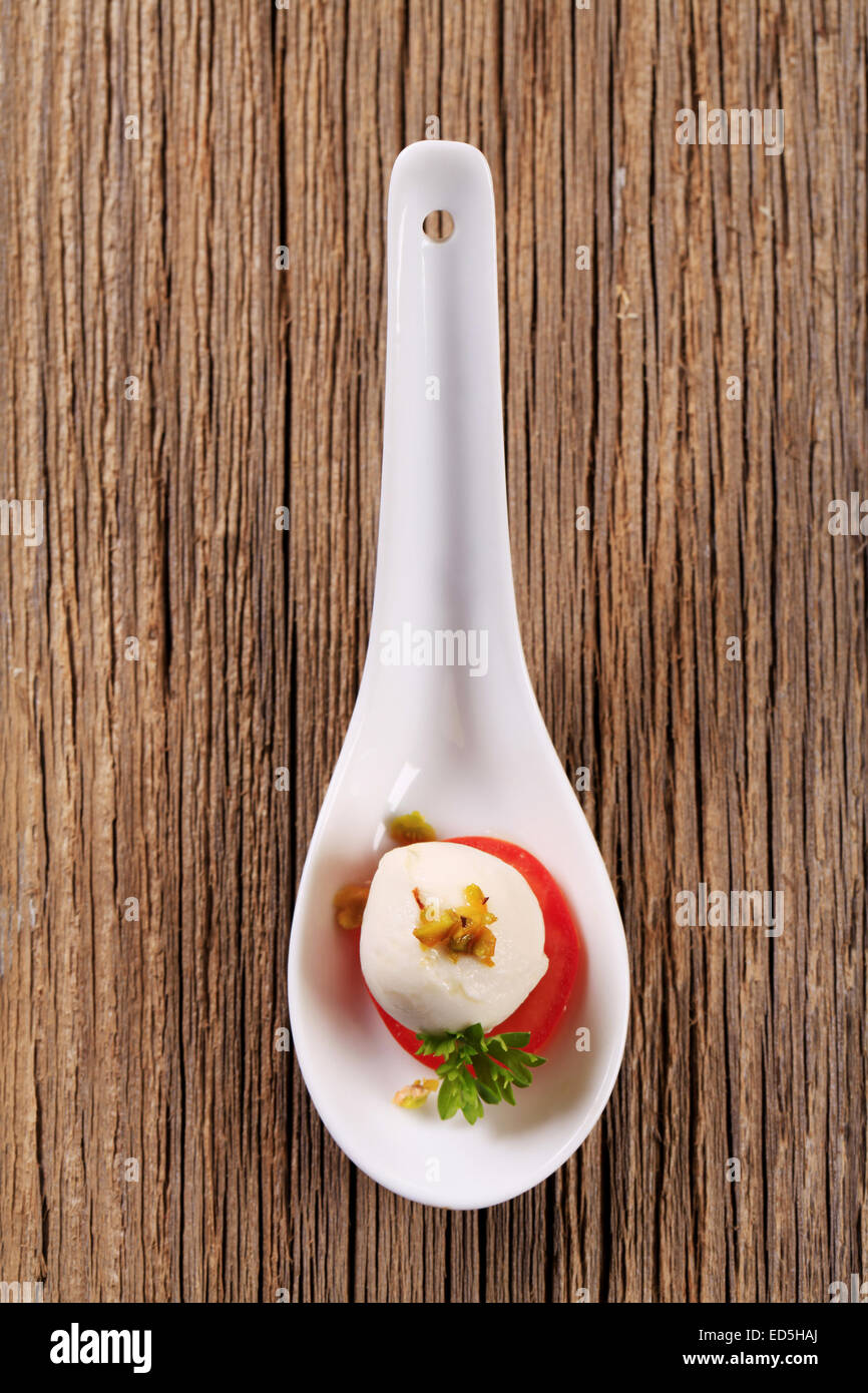 Baby mozzarella e pomodoro sul cucchiaio in porcellana Foto Stock