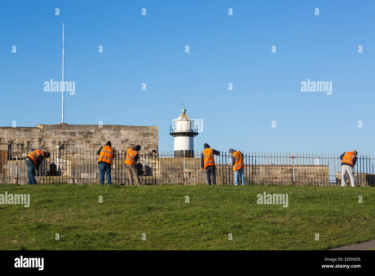 I trasgressori funzionante a Southsea Castle, Portsmouth, effettuare il servizio comunitario; arancione giacche inscritto " Comunità " di reintegrazione del capitale investito Foto Stock