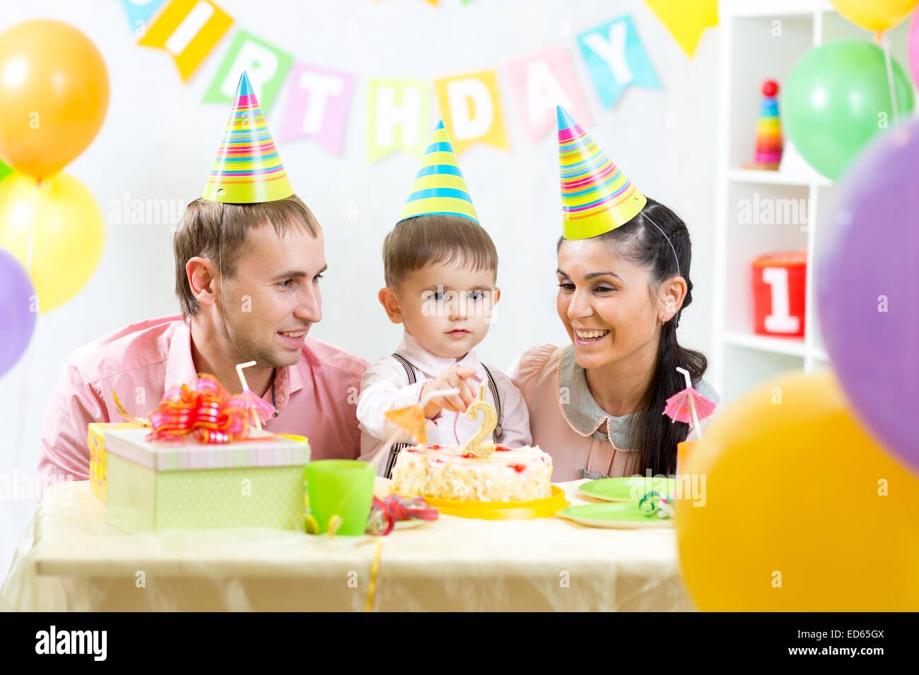 Il capretto con i genitori colpo candele sulla torta di compleanno Foto Stock
