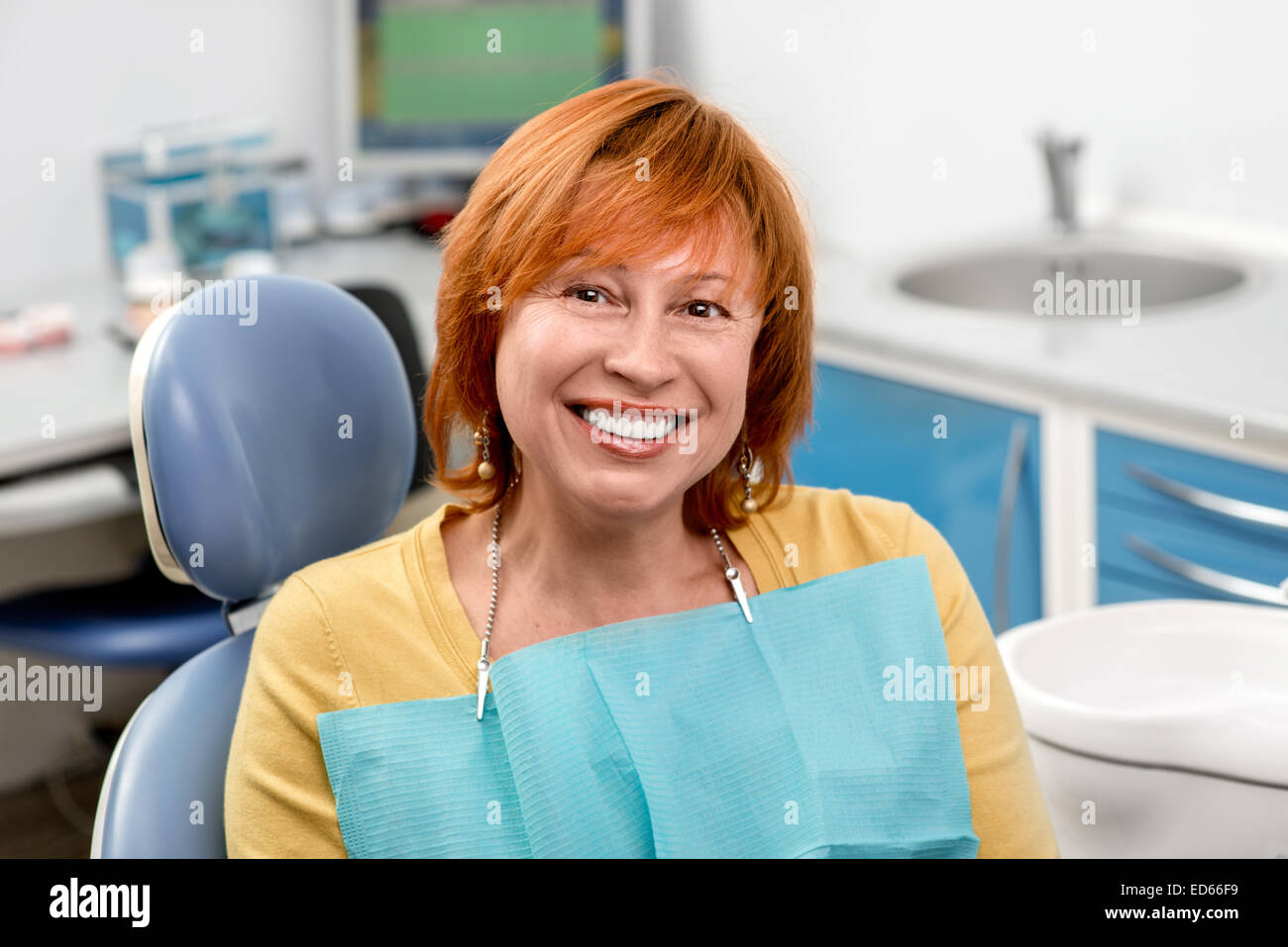 Sorridente donna senior con nuovi impianti dentali seduto in studio dentistico Foto Stock