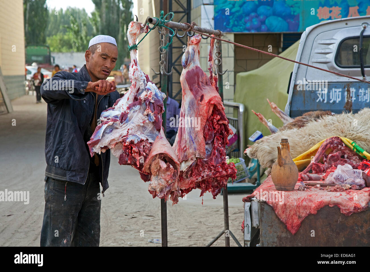 Butcher il taglio di carne dal suo pickup truck nel villaggio Waxxari, oasi cittadina nel deserto Taklamakan, provincia dello Xinjiang, Cina Foto Stock