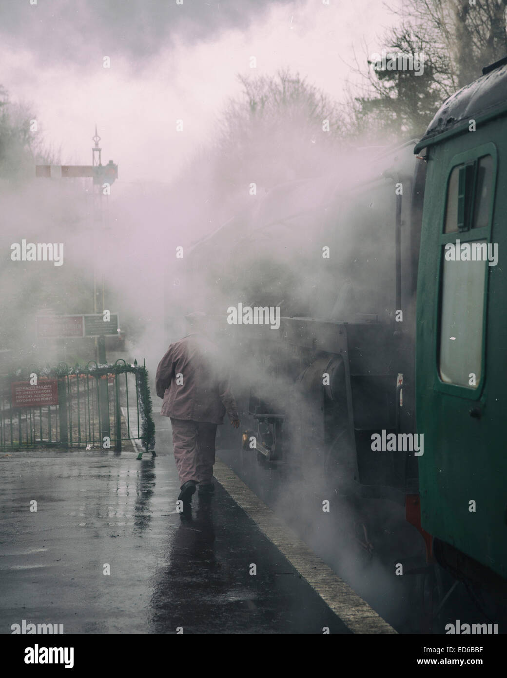 Una pedana uomo si prepara a bordo conserve BR Standard di Classe 9F 2-10-0 locomotiva a vapore tra le nuvole di vapore in Hampshire Foto Stock