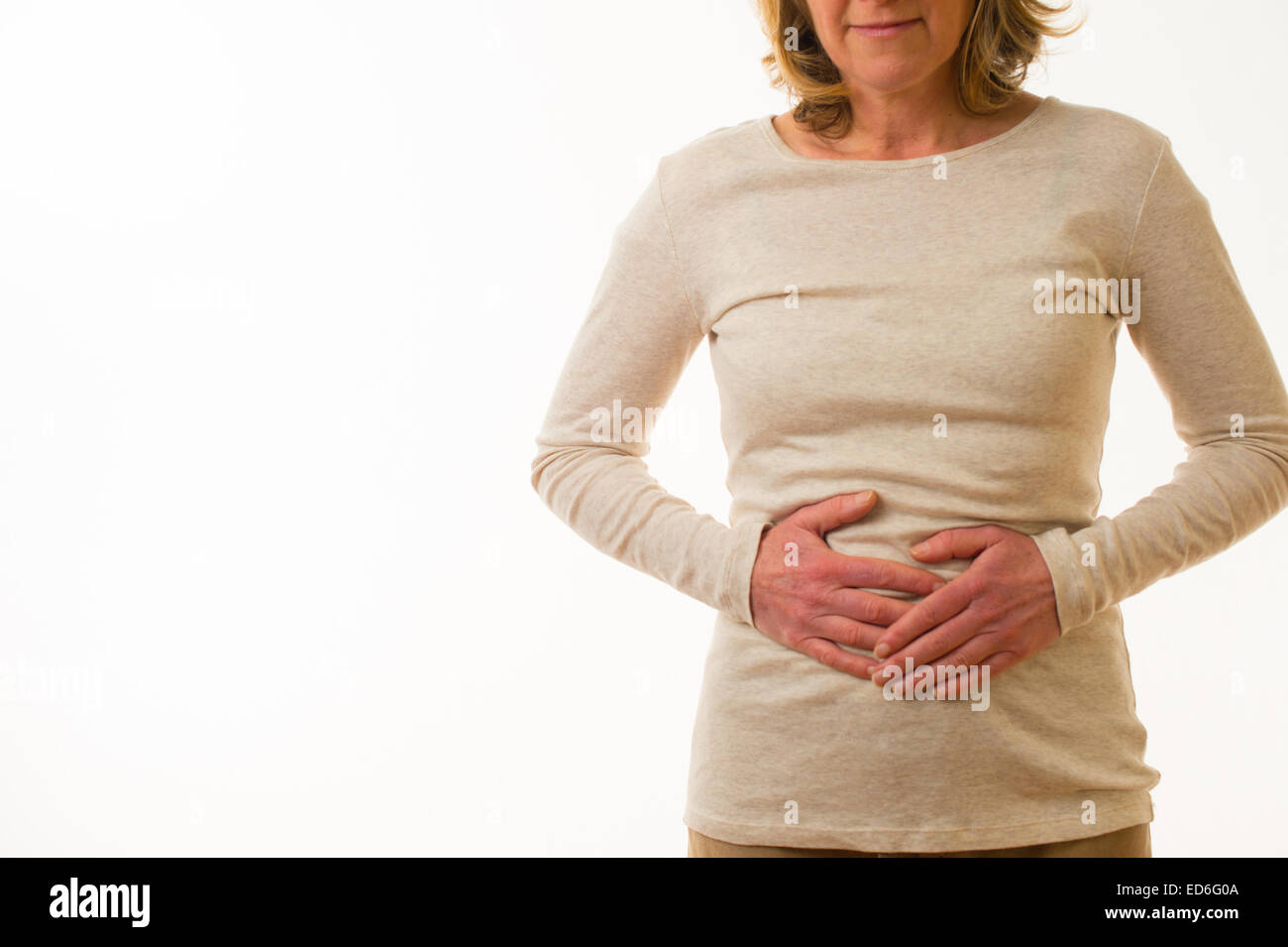 Un quarantenne donna caucasica con il mal di pancia periodo pre mestruale  dolori di tensione strofinando il doloroso dello stomaco in piedi contro  uno sfondo bianco. Regno Unito Foto stock - Alamy