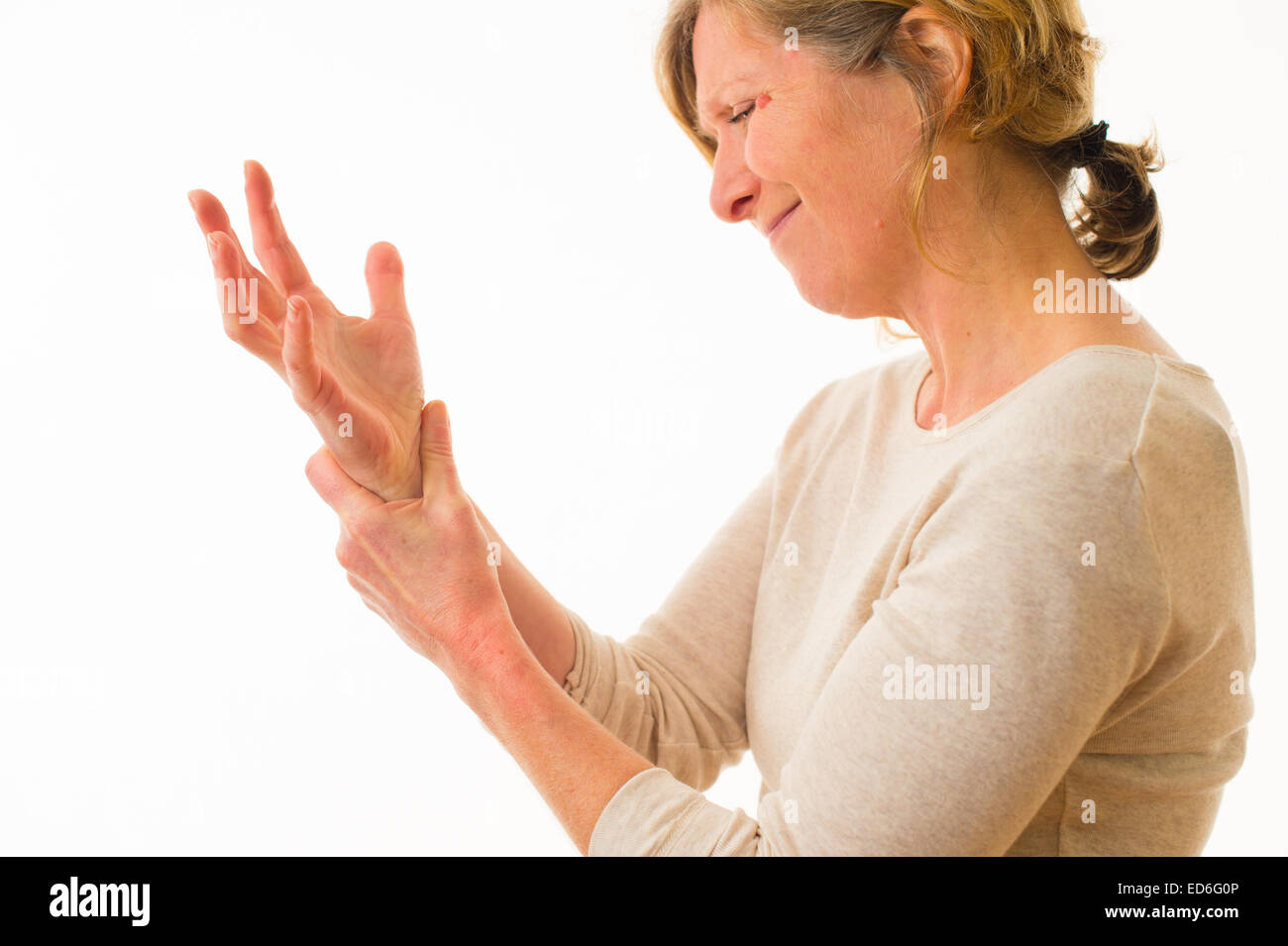 Un quarantenne donna caucasica con artrite dolorosa delle articolazioni della mano e del polso dita, strofinando il polso per il sollievo dal dolore, contro uno sfondo bianco. Regno Unito Foto Stock