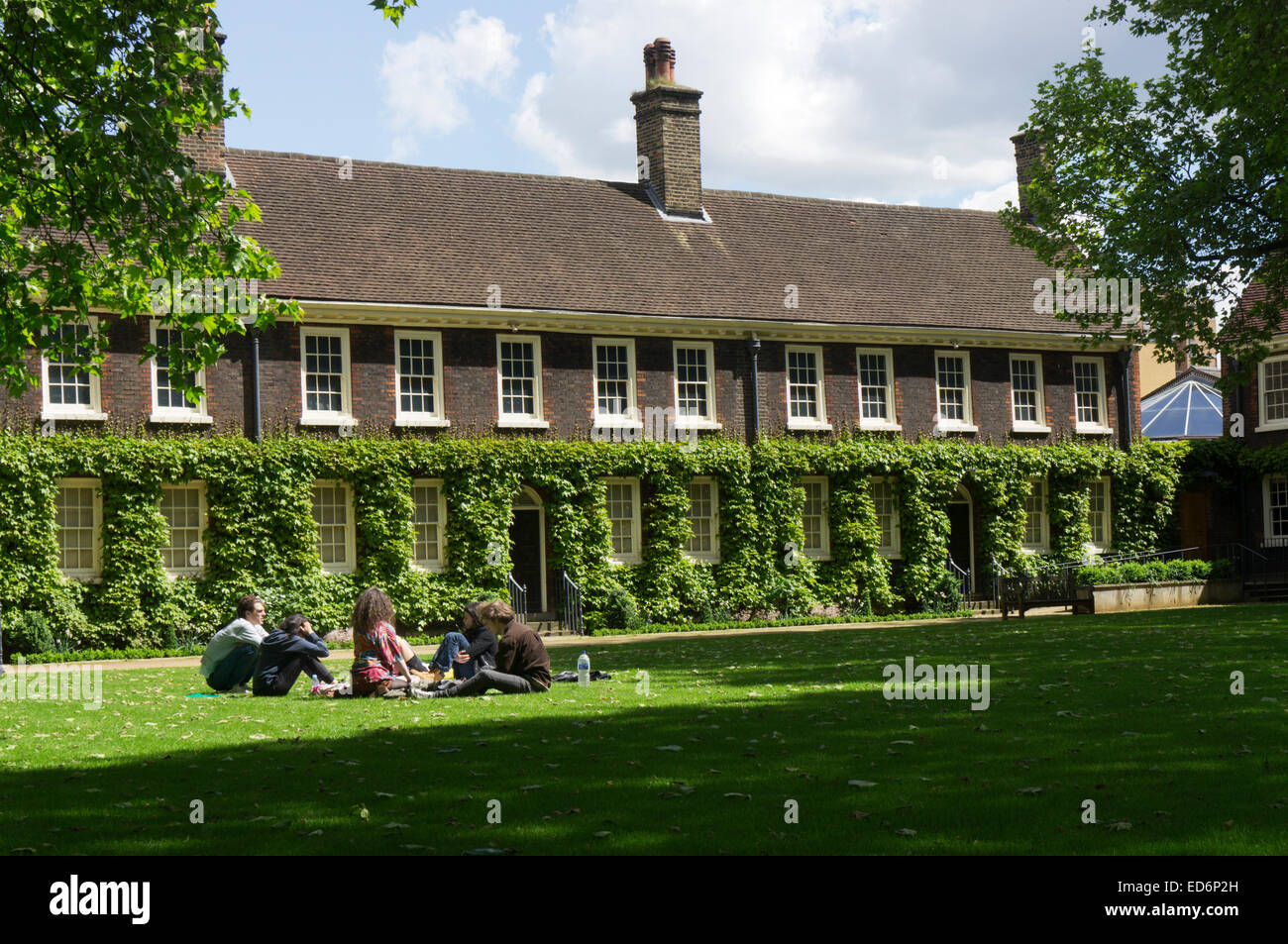 I giovani si rilassano sul prato erboso di fronte al Museo Geffrye, ora il Museo della Casa, a Shoreditch, Londra Est. Foto Stock