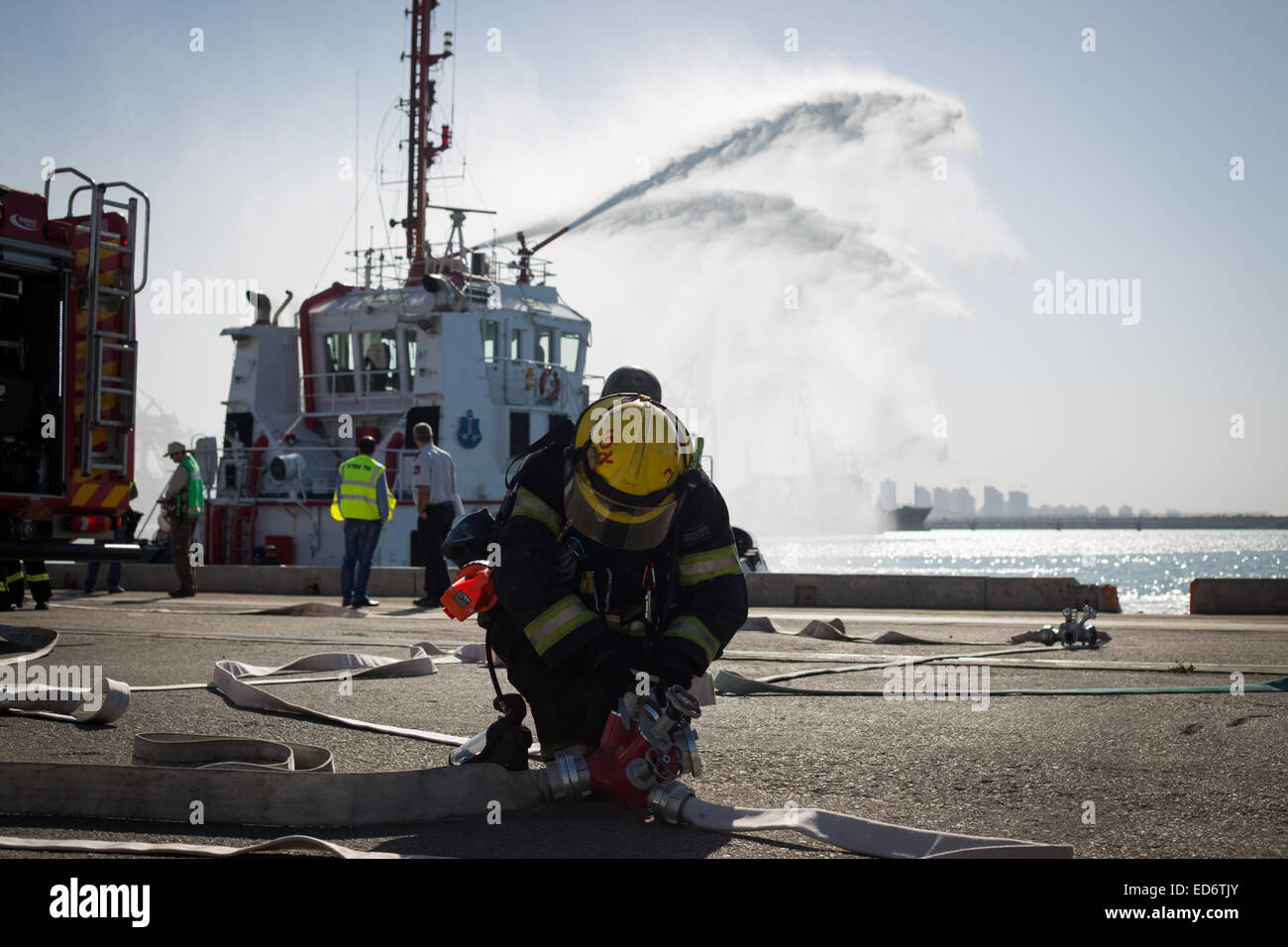 (141230) -- Gerusalemme, 30 dic. 2014 (Xinhua) -- Un israeliano fire fighter assiste un trapano di soccorso al porto di Ashdod, Israele sud, il 29 dicembre 2014. Il salvataggio del trapano, regolarmente praticata come uno scenario, era basato su una infiltrazione terroristica con l'uso di materiali pericolosi dal mare. (Xinhua/JINI/Albert Sadikov) Foto Stock