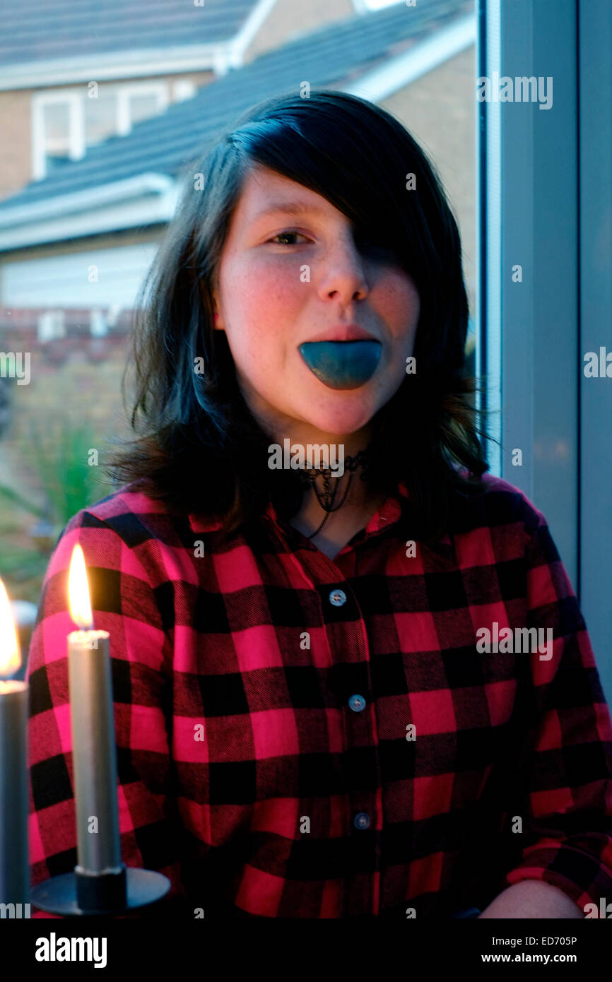 Ragazza di dodici anni fuori la sua linguetta che è blu scuro da mangiare dolci Foto Stock