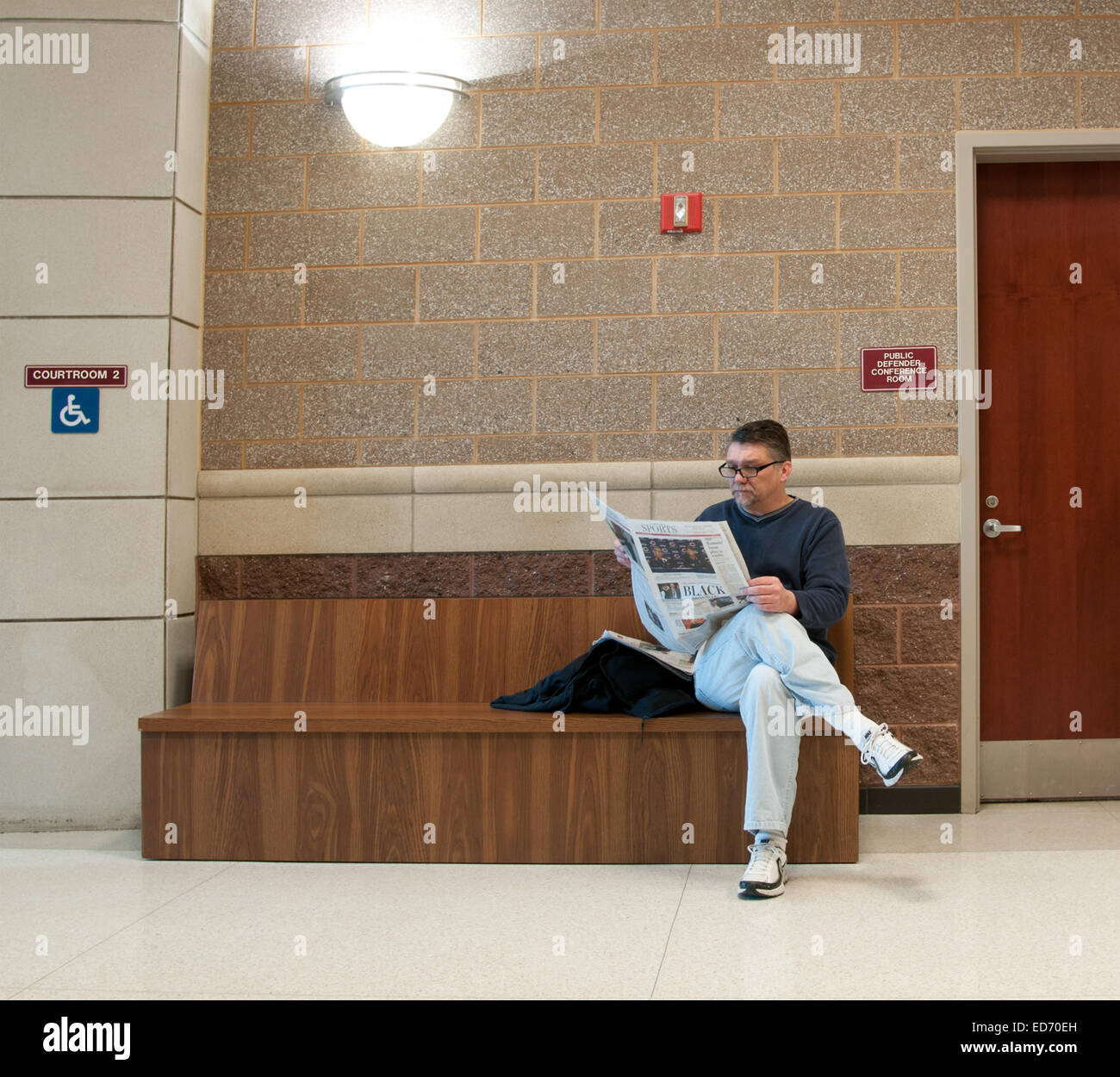 La gente in attesa al di fuori degli uffici dei pubblici ministeri come un uomo legge il suo giornale concernenti le relazioni di colore nero con applicazione della legge. Foto Stock