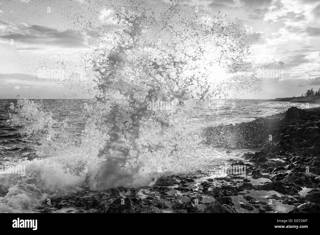 Spruzzare dal famoso fori di soffiaggio sulla costa meridionale di Grand Cayman è illuminato dal sole al tramonto. Foto Stock