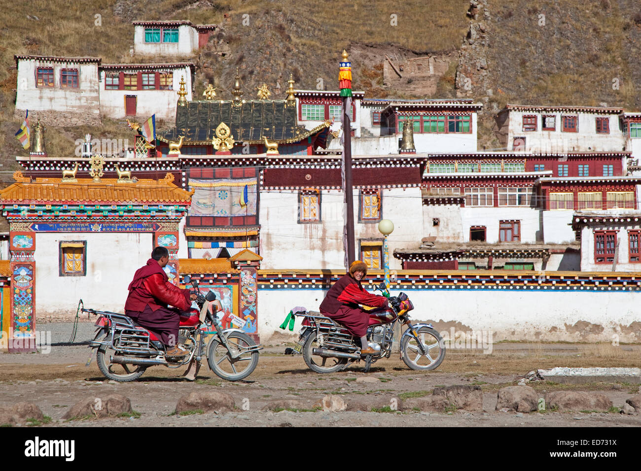 Due giovani monaci tibetani andare in motocicletta nella parte anteriore del monastero tra Sershu Dzong e Sershu / Serxu, nella provincia di Sichuan, in Cina Foto Stock