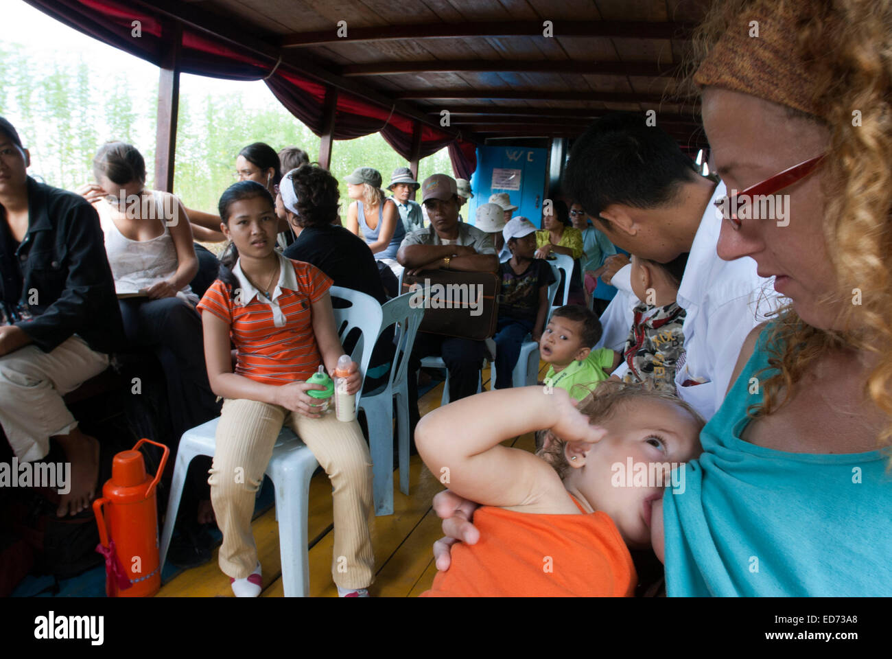 Una madre allattamento al seno di sua figlia baby all'interno della barca sul fiume Sangker. Cambogia. Asia. Viaggio da Battambang a Siemp ri Foto Stock
