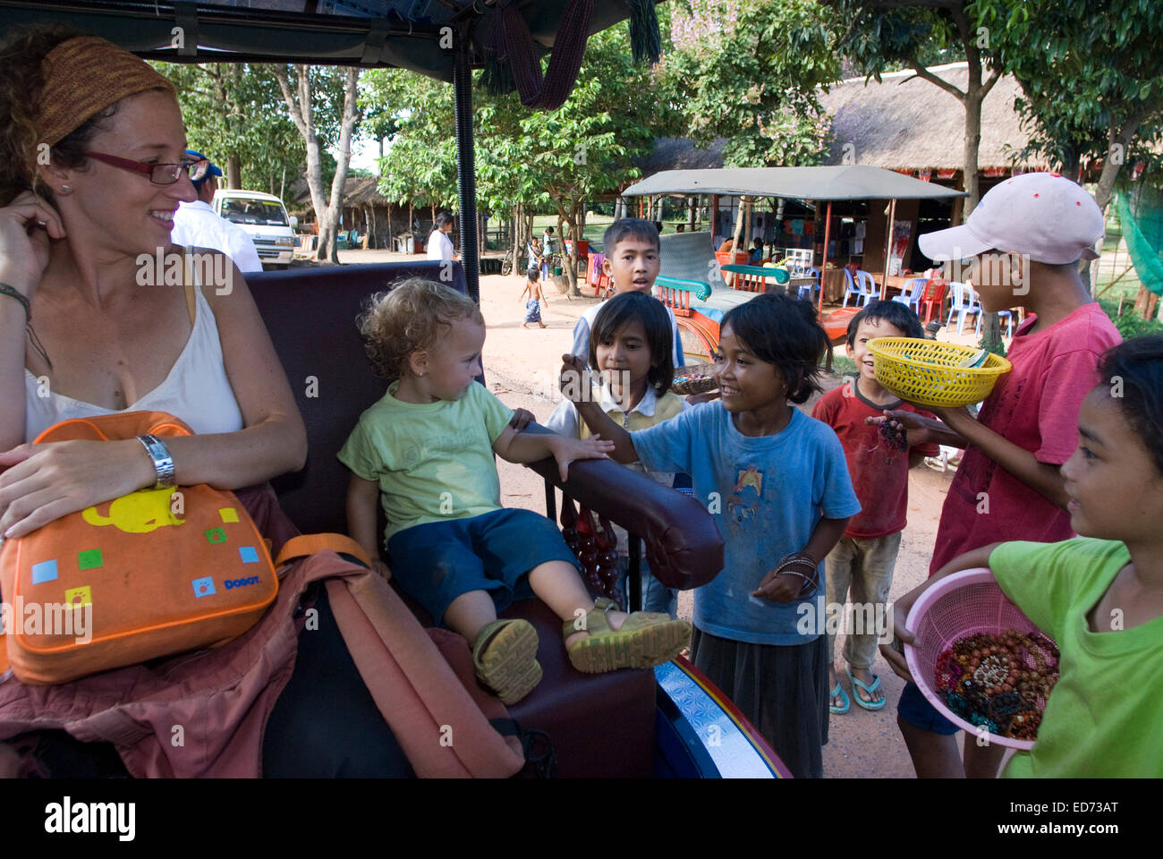 Viaggiare con bambini. Ragazzi la vendita di cartoline e souvenir a una madre a piedi con sua figlia. Preah Khan Temple. Preah Kha Foto Stock