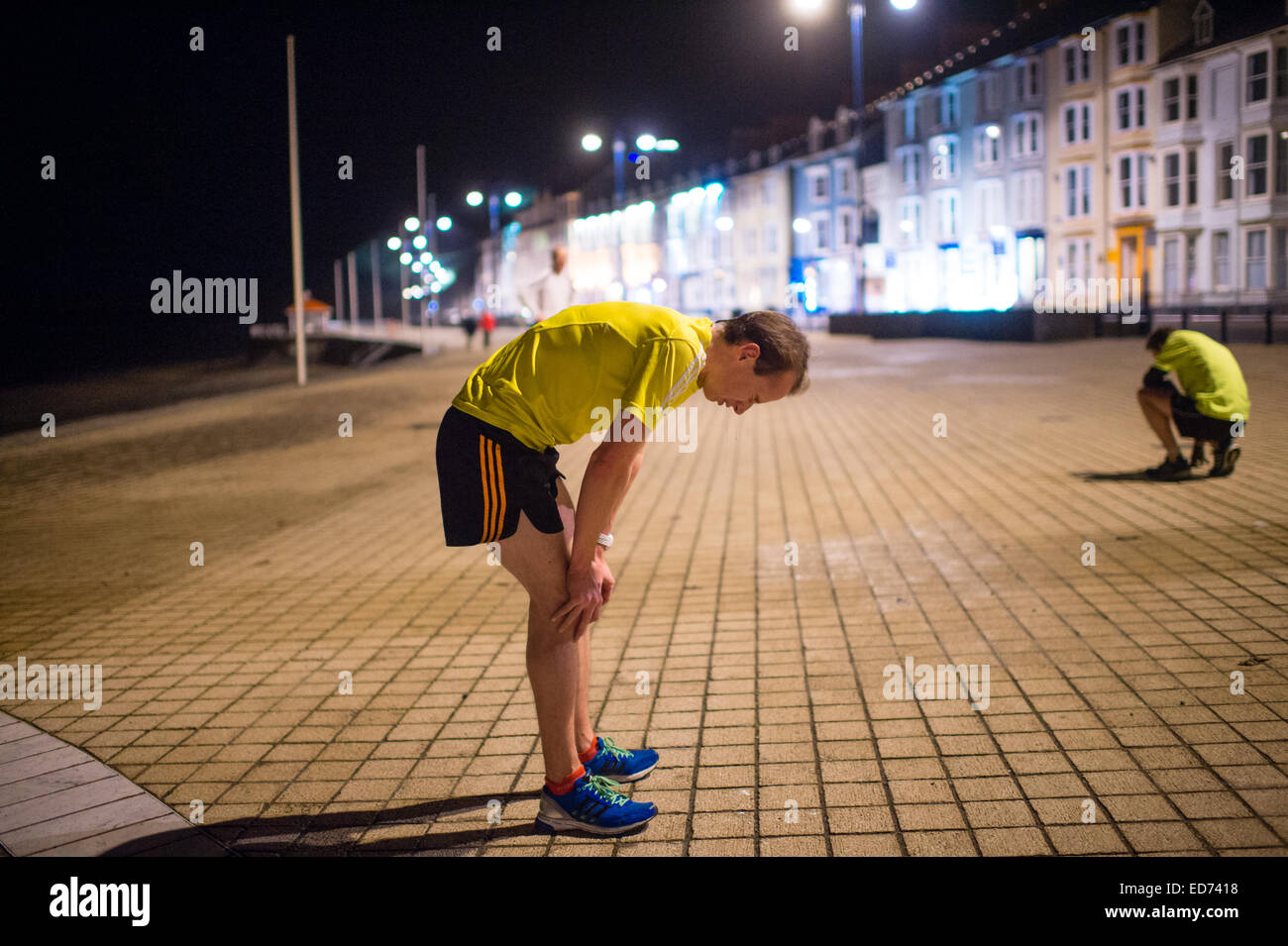 In esecuzione durante la notte: due uomini esaurito ottenendo il fiato dopo un digiuno notturno di 5km corrono lungo Aberystwyth promenade Wales UK Foto Stock