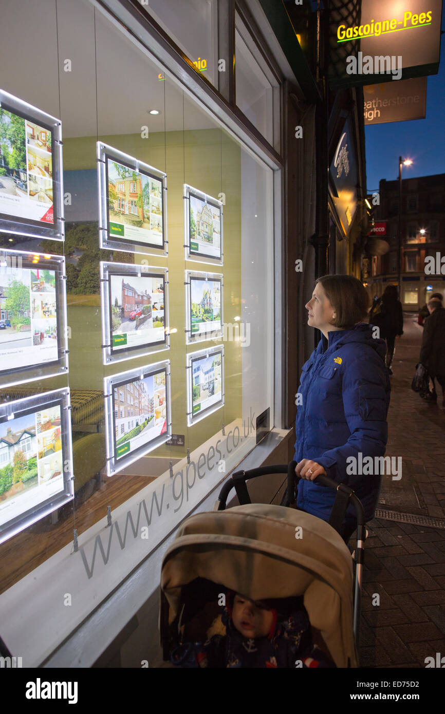 Donna e bambino guarda le proprietà pubblicizzato in un Agenti Immobiliari finestra, Richmond Upon Thames, Esterno Londra, Regno Unito Foto Stock