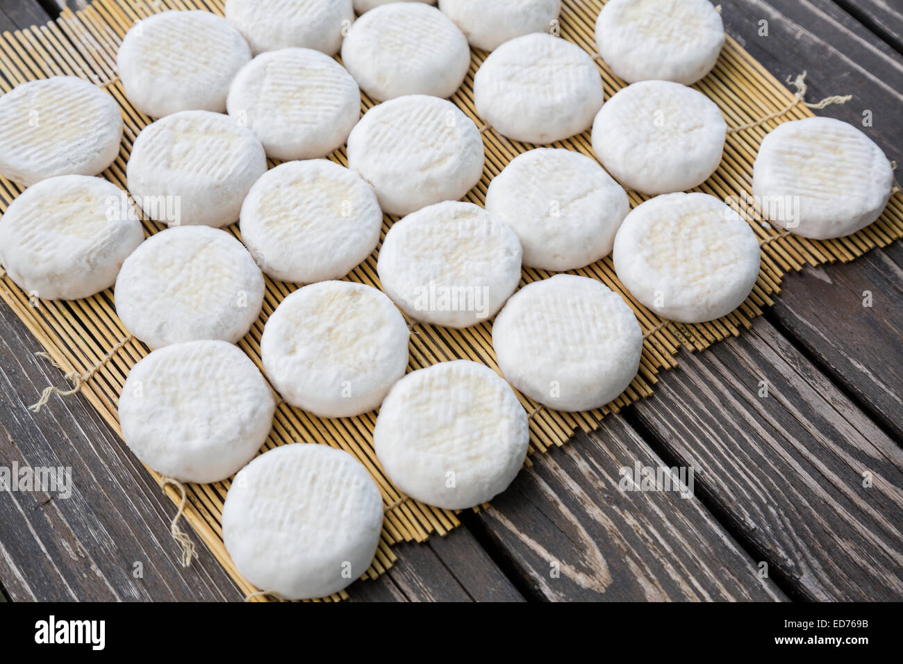 Insieme di piccoli capi di giovani formaggio di capra crottin giacente su tavole di legno Foto Stock