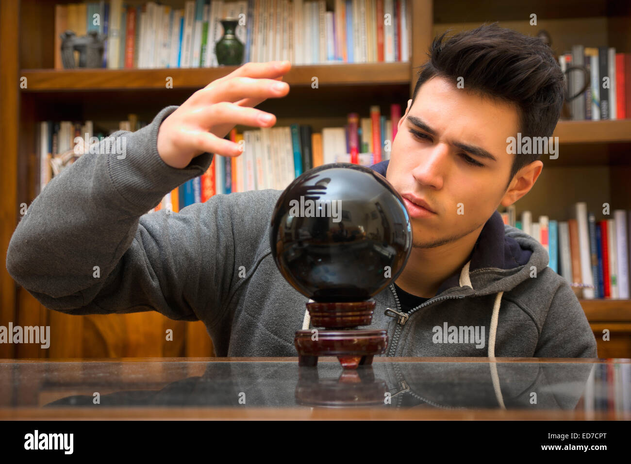 Giovane uomo predire il futuro guardando nella sfera di cristallo Foto Stock