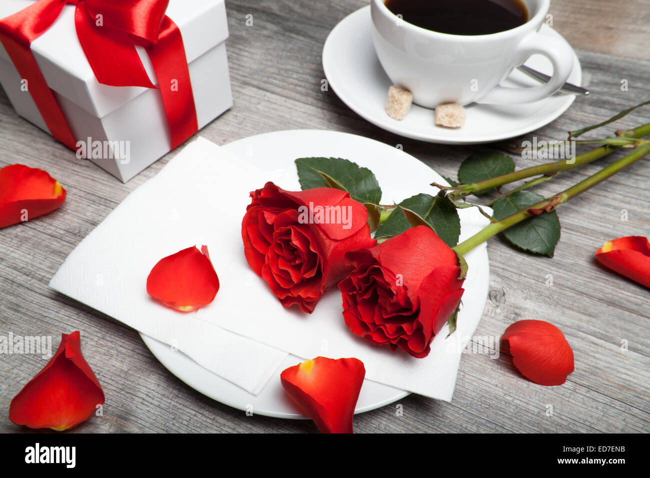 Rose rosse, presente e caffè sul tavolo Foto Stock