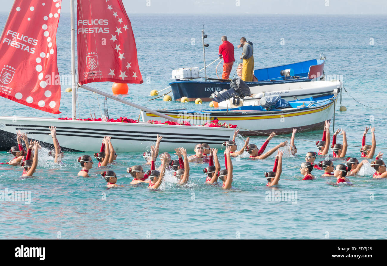 Las Palmas de Gran Canaria, Isole Canarie, Spagna. Il 31 dicembre, 2014. Meteo: nuoto sincronizzato dimostrazione da giovani nuotatori locali sulla spiaggia di Las Canteras a Las Palmas come parte della città per i festeggiamenti di Capodanno. I pescatori operanti sulla barca in background. Credito: ALANDAWSONPHOTOGRAPHY/Alamy Live News Foto Stock