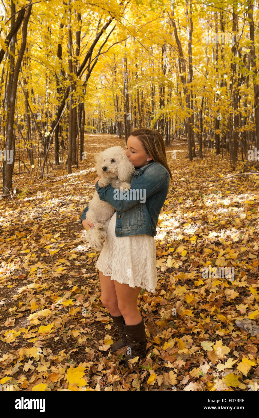 A piena lunghezza Ritratto di giovane donna teen sul sentiero forestale baciare cane in autunno Foto Stock