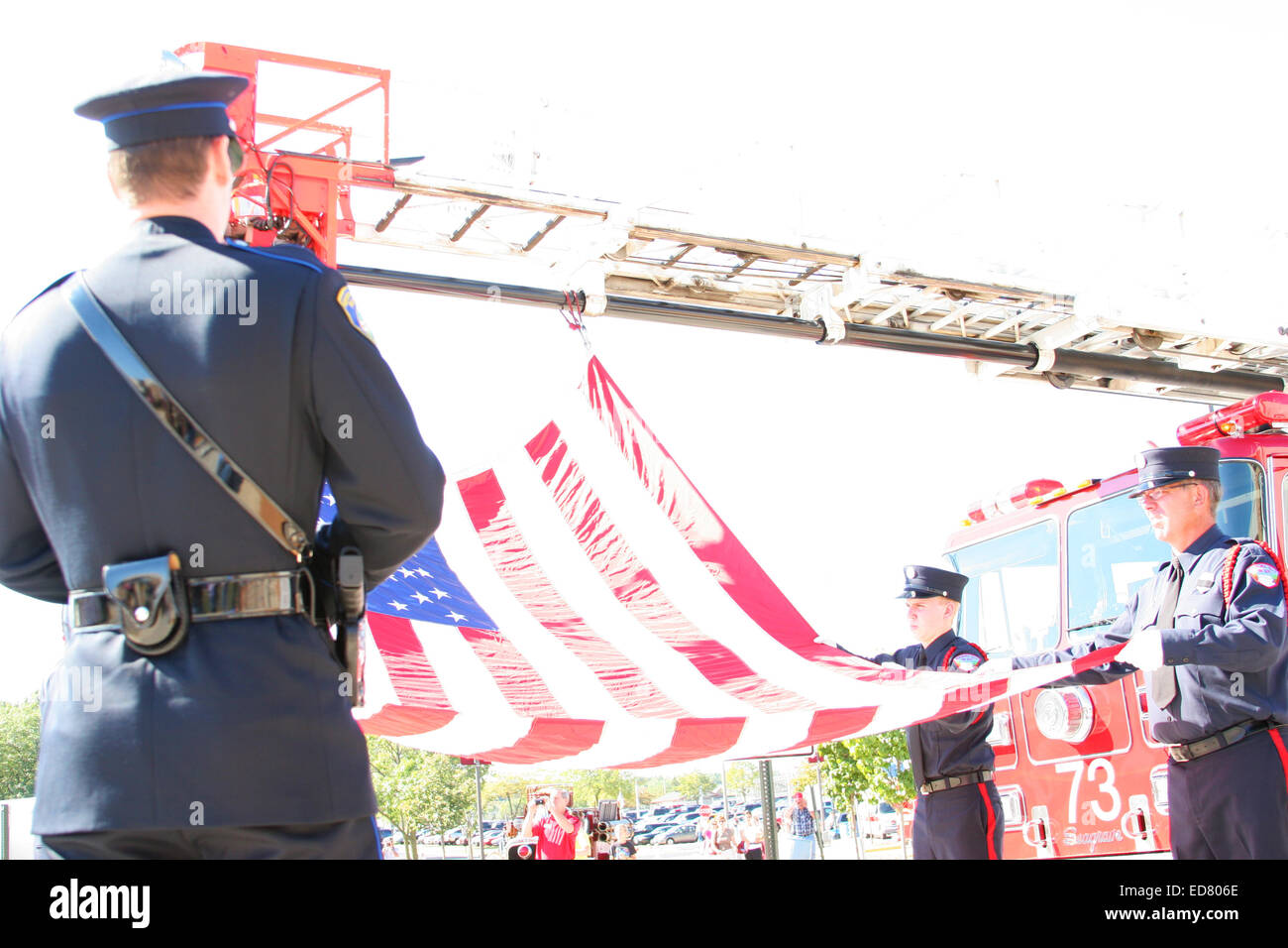 Un funzionario di polizia con la bandiera americana di essere appeso ad un reparto antincendio scaletta Foto Stock