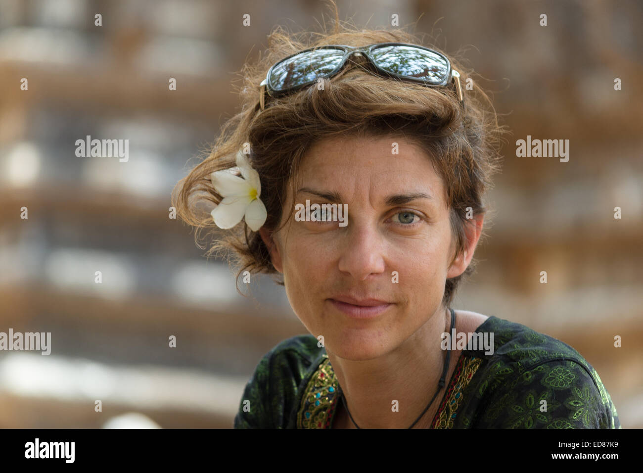 Ritratto di signora matura con il frangipani fregio floreale in tradizionale costume indiano. Luce naturale, pelle naturale. Foto Stock