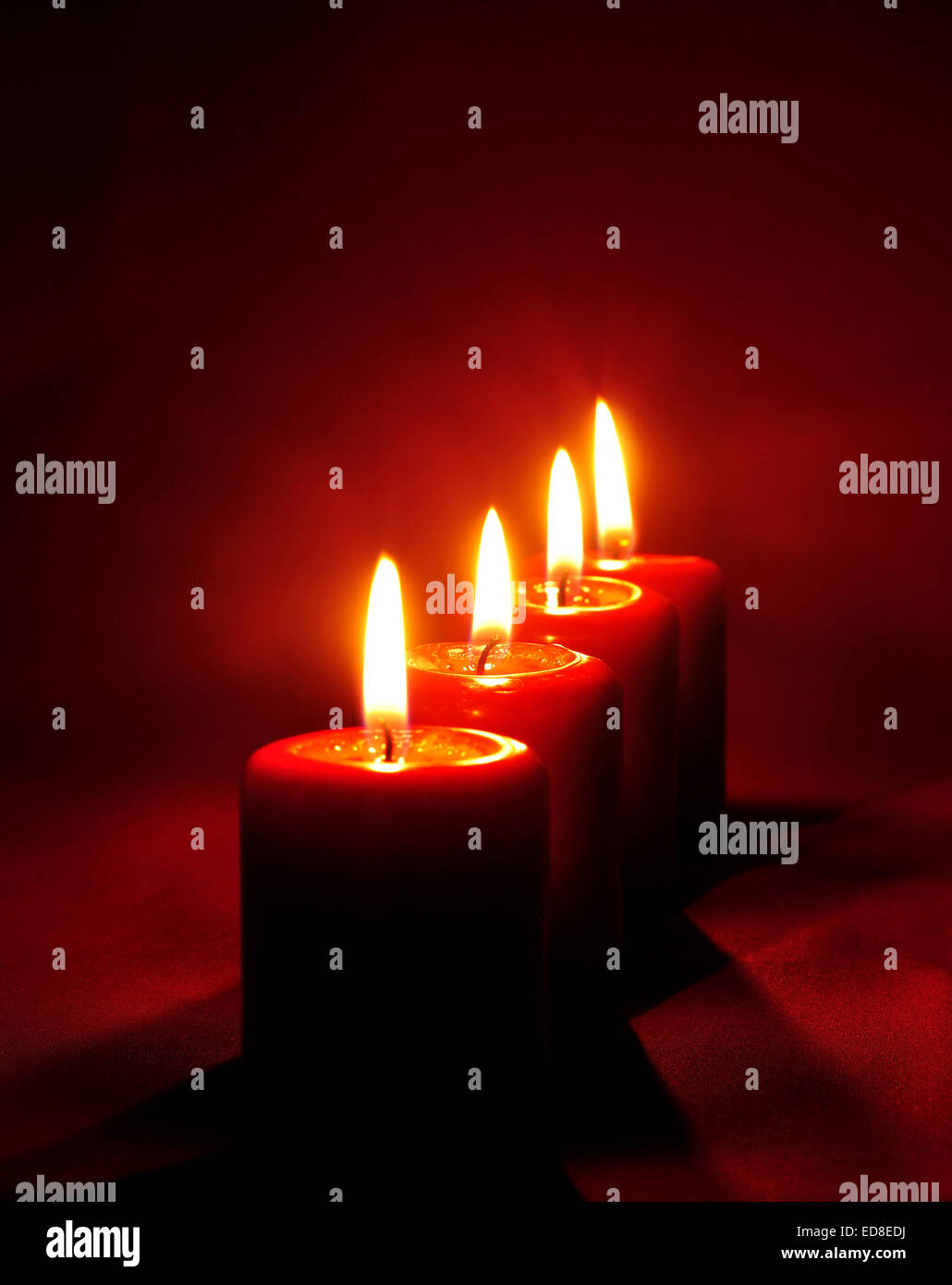 Candele rosse di fiamma con sfondo rosso incandescente al buio. Foto Stock