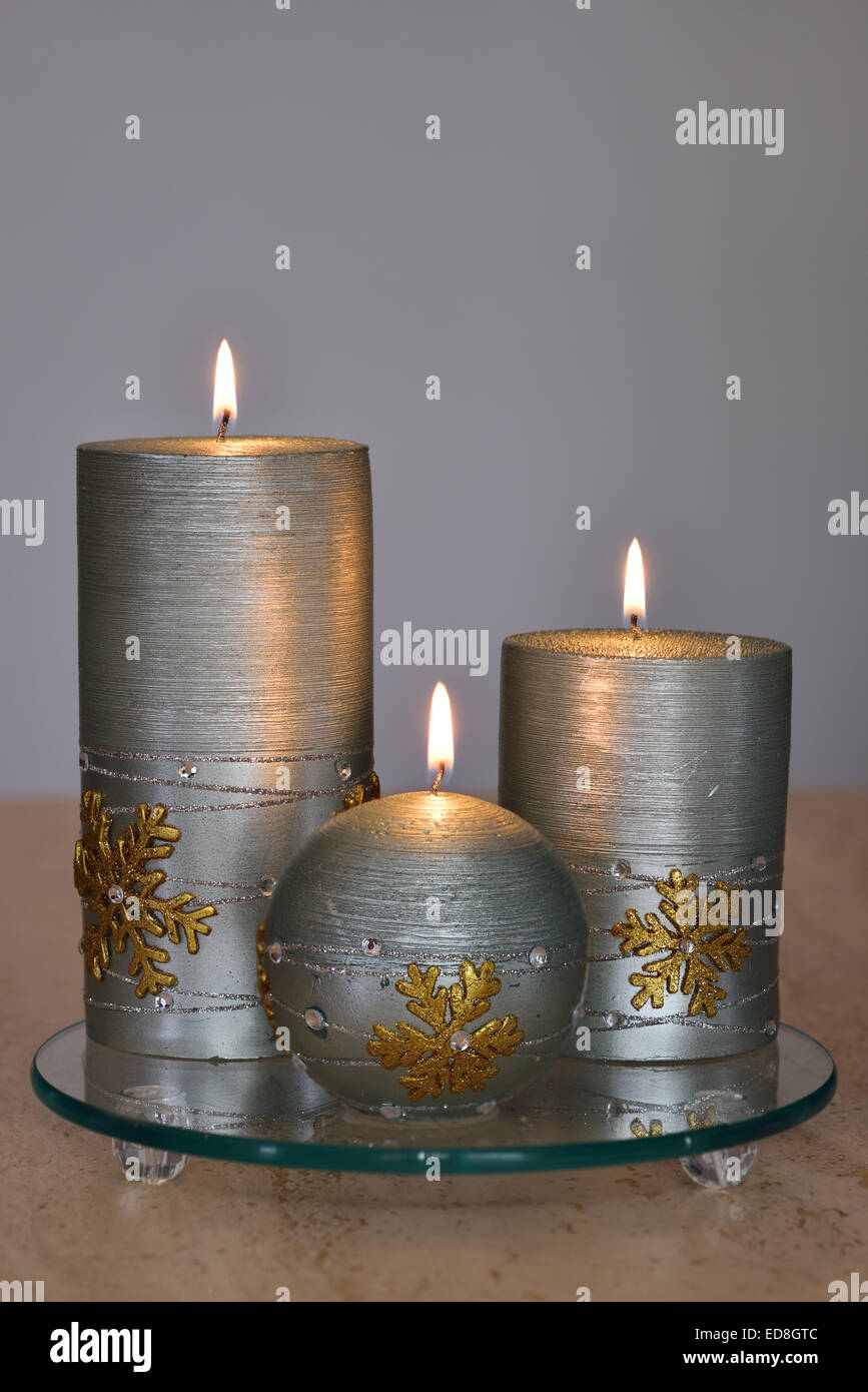 Tre candele color argento con fiamme sul tavolo di pietra e lo sfondo grigio Foto Stock