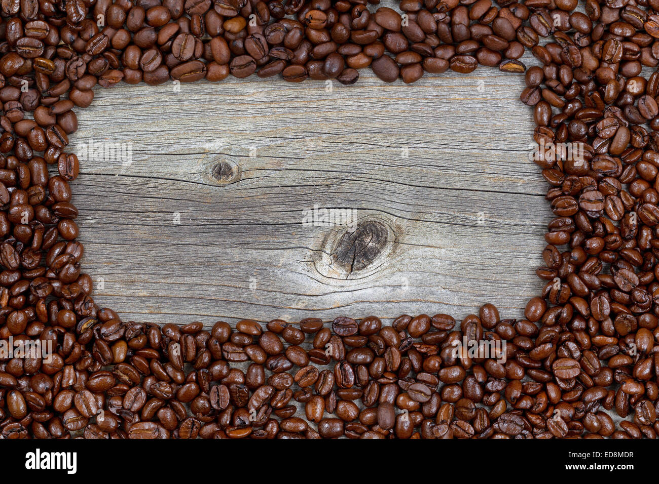 Close up di caffè tostato in grani, formando una forma rettangolare, su rustiche naturalmente invecchiato il legno Foto Stock