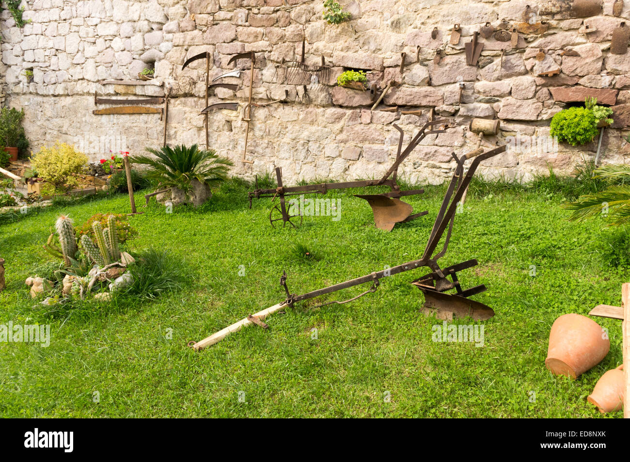 Aratro e vecchi utensili da giardinaggio in un verde prato Foto Stock