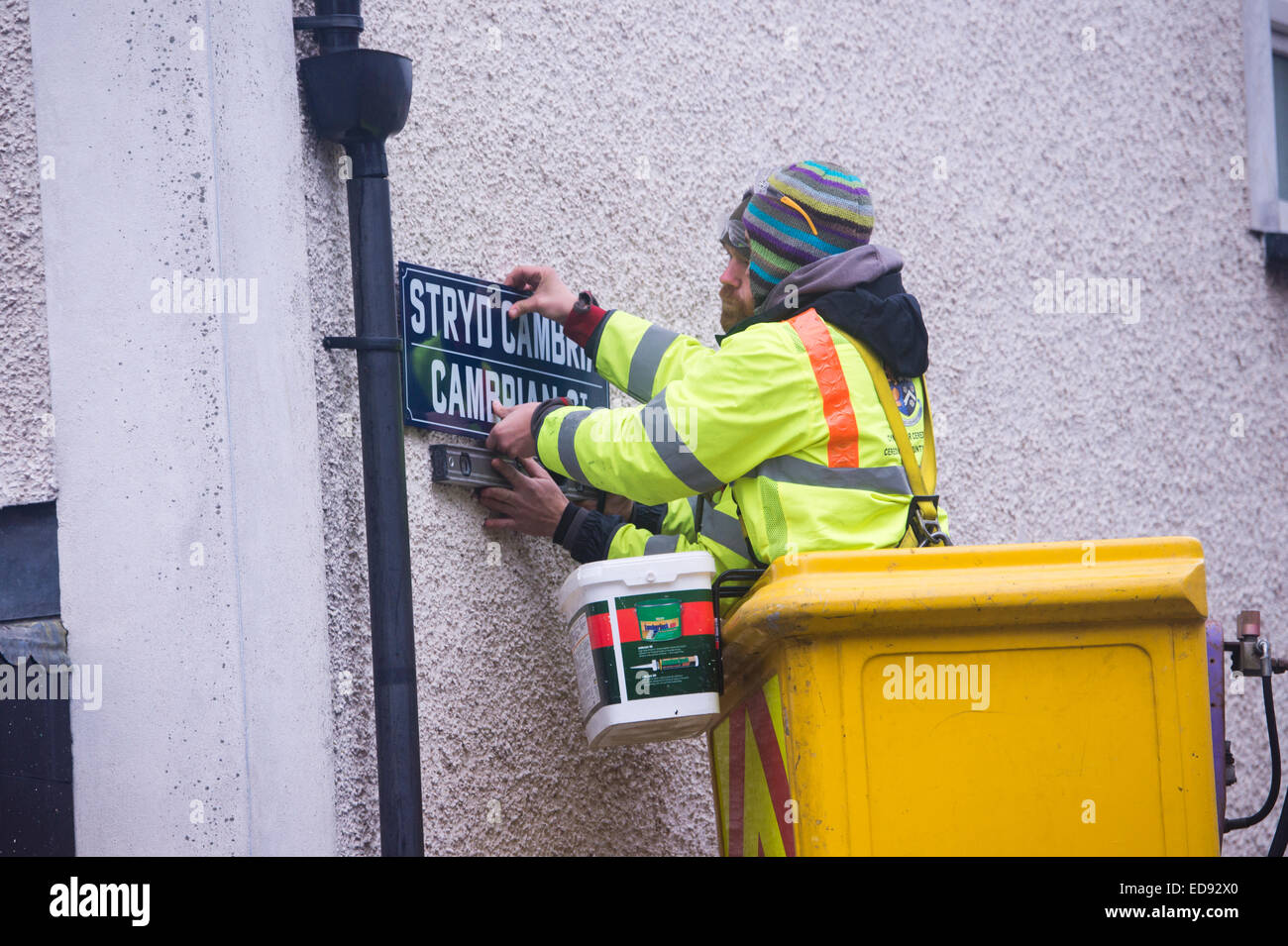 Due autorità locale (Ceredigion County Council) manodopera diretta ai lavoratori dipendenti in un 'cherry picker' sostituendo il segno sul Cambriano Street , Aberystwyth, con nuove versioni con "patrimonio" il carattere tipografico, Wales UK Foto Stock