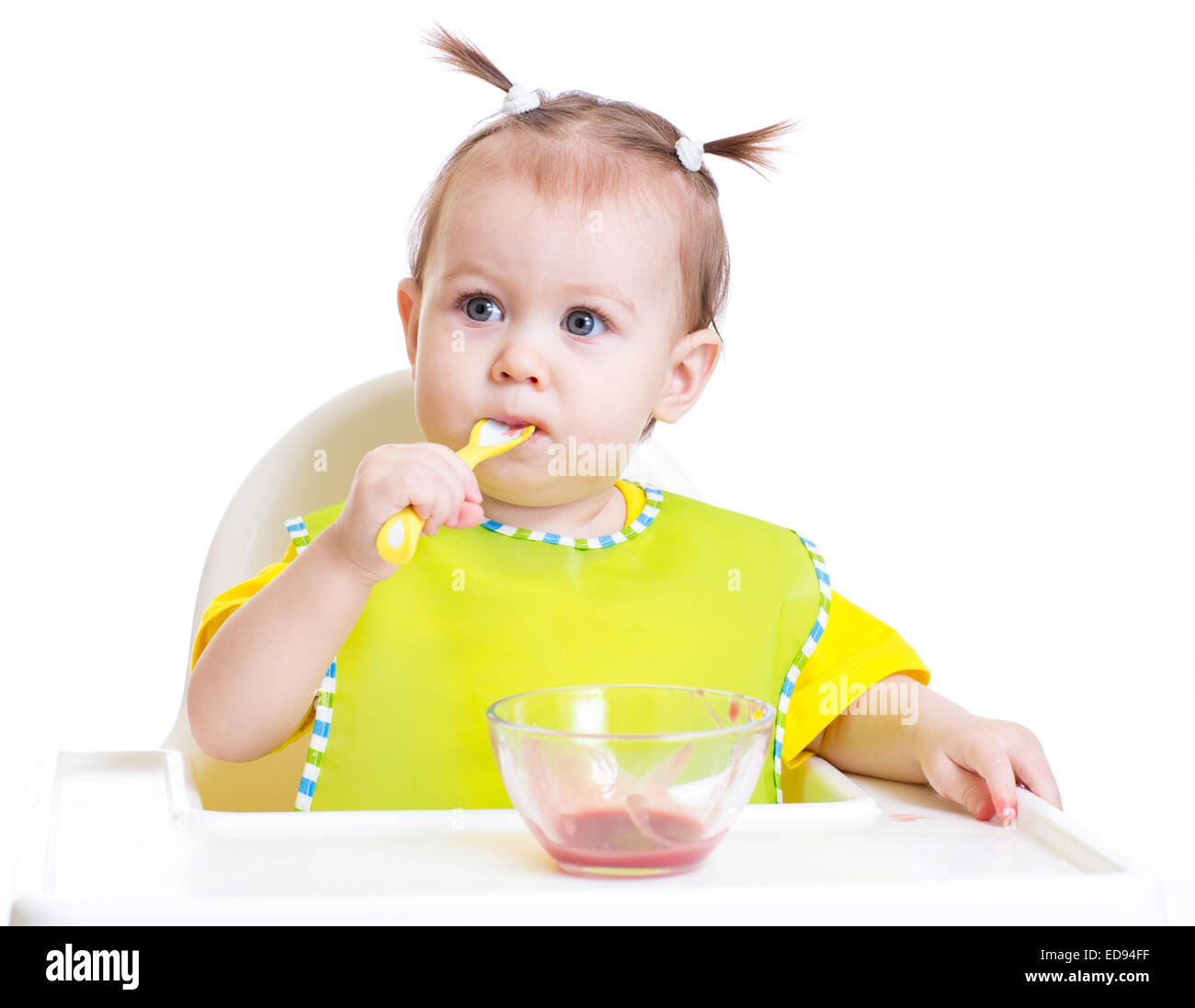 Baby mangiare con il cucchiaio seduta a tavola Foto Stock