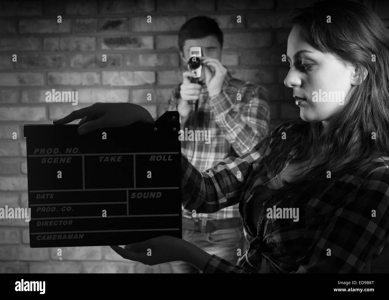 Grave giovane donna azienda battaglio Board con il giovane fotografo maschio all'indietro. Catturate in monocromatico. Foto Stock