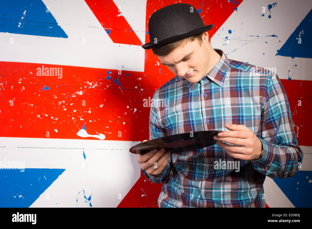 Close up uomo bello nel quartiere alla moda di outfit Holding vinil registrare la piastra anteriore in Gran Bretagna Flag Stampa Foto Stock