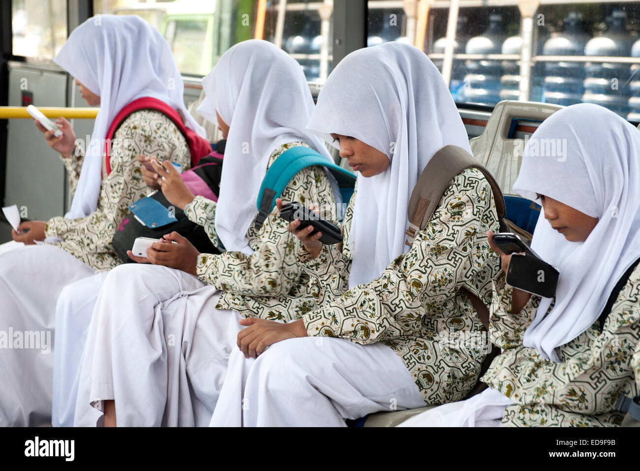 Scuola Balinese ragazze con i loro telefoni intelligenti su un bus di Bali, Indonesia. Foto Stock