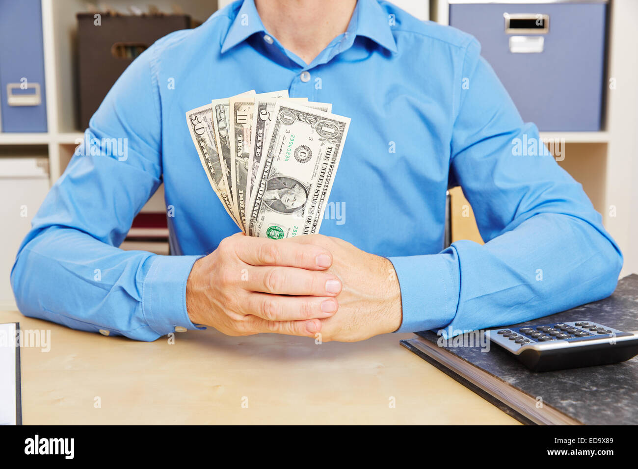 Mani tenendo molte fatture del dollaro come la ventola sulla scrivania Foto Stock