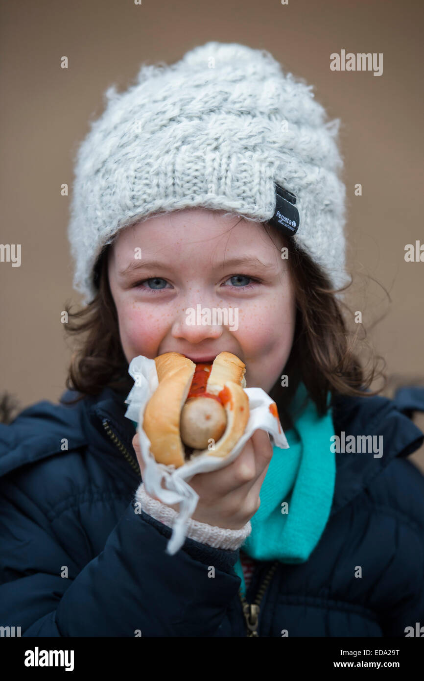 Londra, Regno Unito. 01 gen 2015. Una ragazza gode di un hot dog. Winter Wonderland di Hyde Park contuinues per attirare grandi folle da tutti i segmenti della società di Londra - famiglie e adulti di tutte le età sembrano essere cercando le ultime gocce di spirito di festa da partecipazione in fiera del divertimento attività e lato mostra come pure da bere e mangiare alimenti calorici. Sorrisi sono abbastanza in approvvigionamento corto a parte da ragazzi prendere ballons e persone sulle montagne russe. Credito: Guy Bell/Alamy Live News Foto Stock