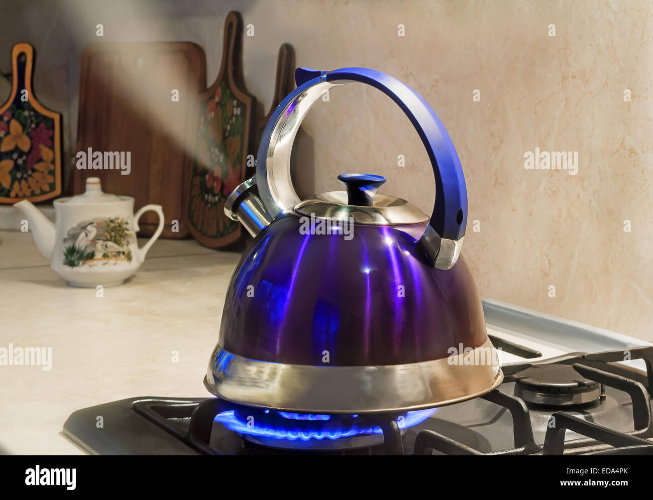 Bollitore blu con un segnale di acqua bollente e getto di vapore dal becco è sulla masterizzazione di fornello a gas Foto Stock