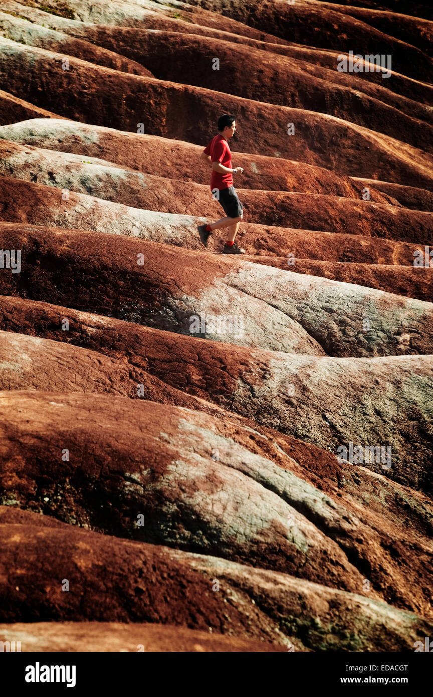 Uomo in esecuzione in badlands Foto Stock