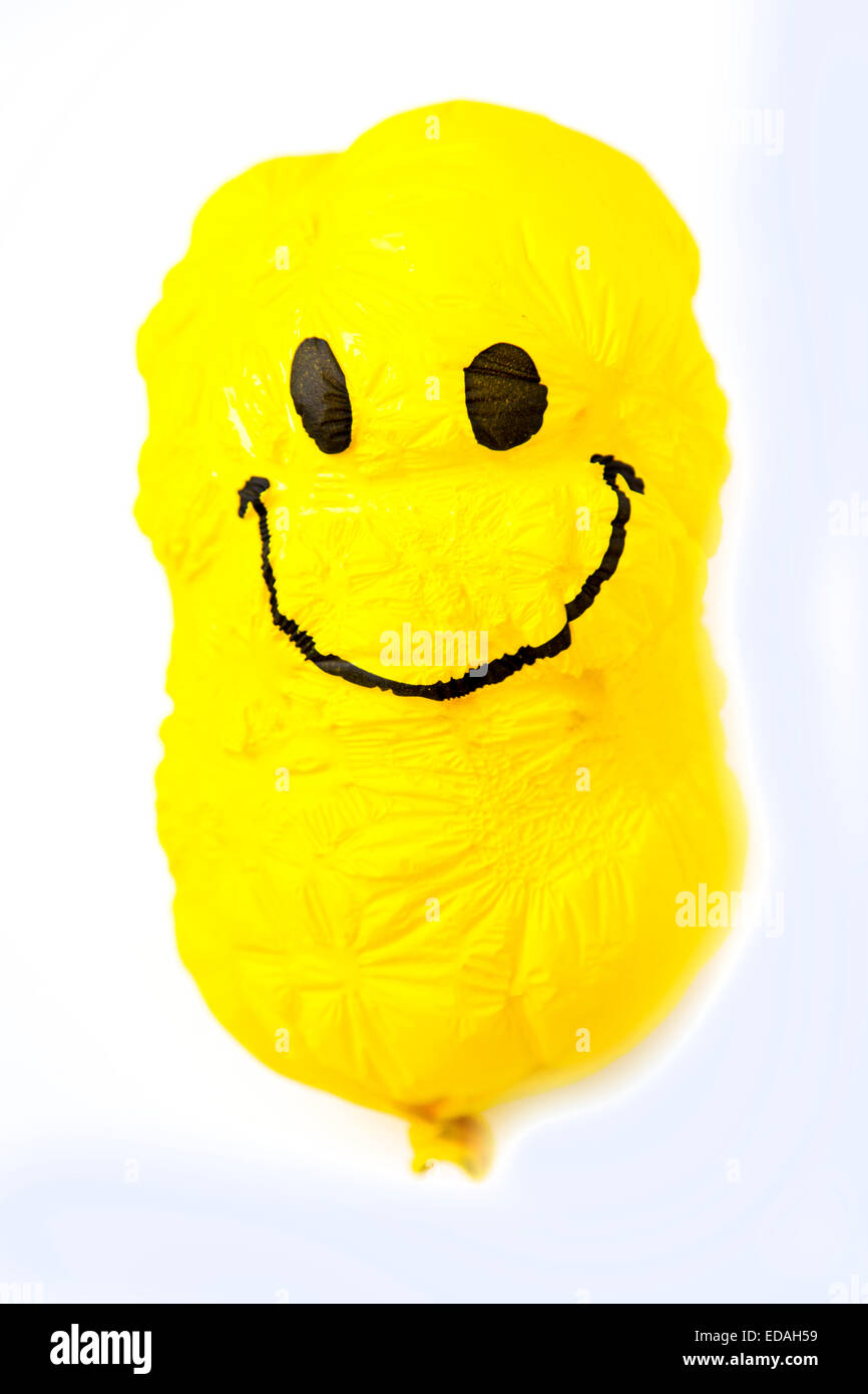 Vecchio palloncino, giallo, raggrinzito con cordiale Smiley face, sunken, stropicciata Foto Stock