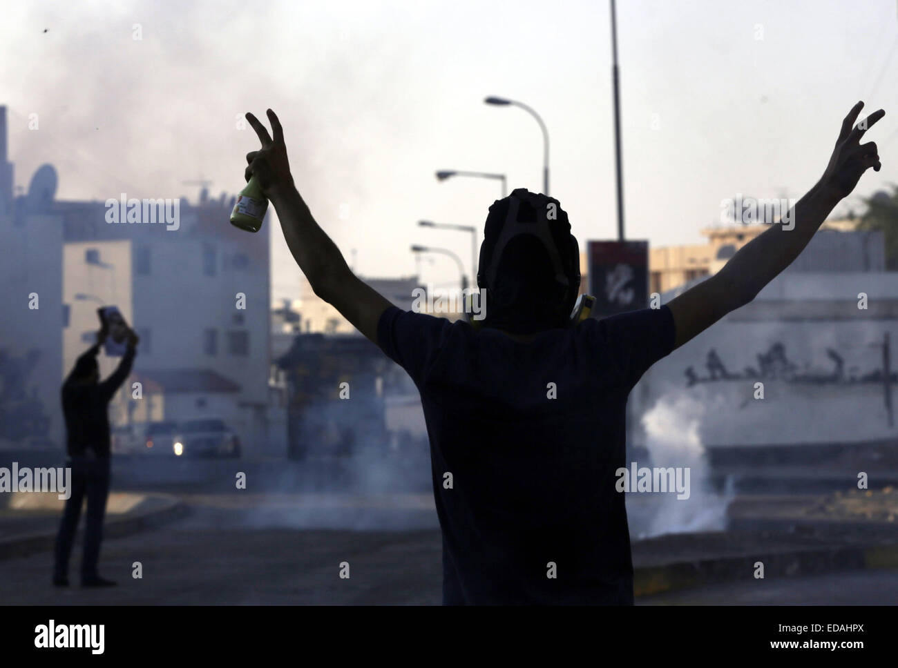 Manama, Bahrain. 3 gennaio, 2015. Un Bahraini anti-government protester gesti durante uno scontro con anti-sommossa poliziotti in Bilad Al Qadeem, vicino a Manama, la capitale del Bahrein, Gen 3, 2015. Scontro ha eruttato in molte parti del Bahrain tra anti-sommossa polizia e dimostranti che chiedono la liberazione del paese sciita principale leader dell opposizione lo sceicco Ali Salman. © Hasan Jamali/Xinhua/Alamy Live News Foto Stock