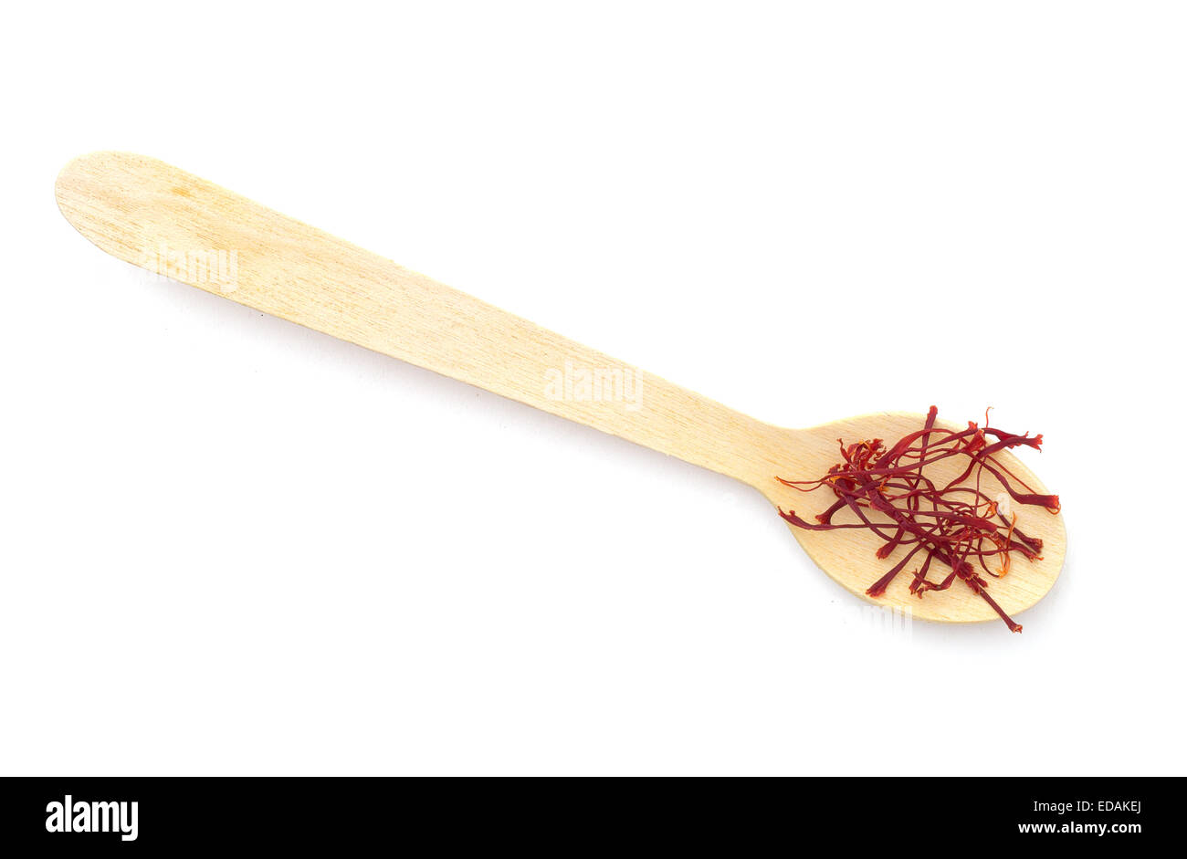 Rosso di filamenti di zafferano sul piccolo cucchiaio di legno. Su bianco. Foto Stock