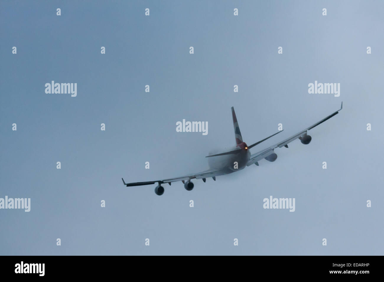 Il 3 gennaio 2015, l'aeroporto di Heathrow di Londra. Basse nubi e pioggia offrono le condizioni ideali per osservare la scia dei vortici e 'pelosità' come l'umidità si condensa sulle ali di aerei di atterraggio. Con la pista visibile solo all'ultimo minuto, vari piani dovevano eseguire un 'go-round", abbandonando i loro primi tentativi di terra. Nella foto: un British Airways Boeing 747 scompare nelle nuvole basse momenti dopo il decollo da Londra Heathrow. Foto Stock