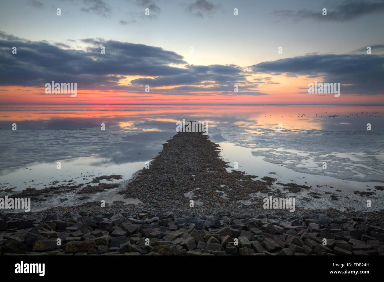 Pier sotto Rising Sun a marea di declino, a distanza di alcuni uccelli Foto Stock